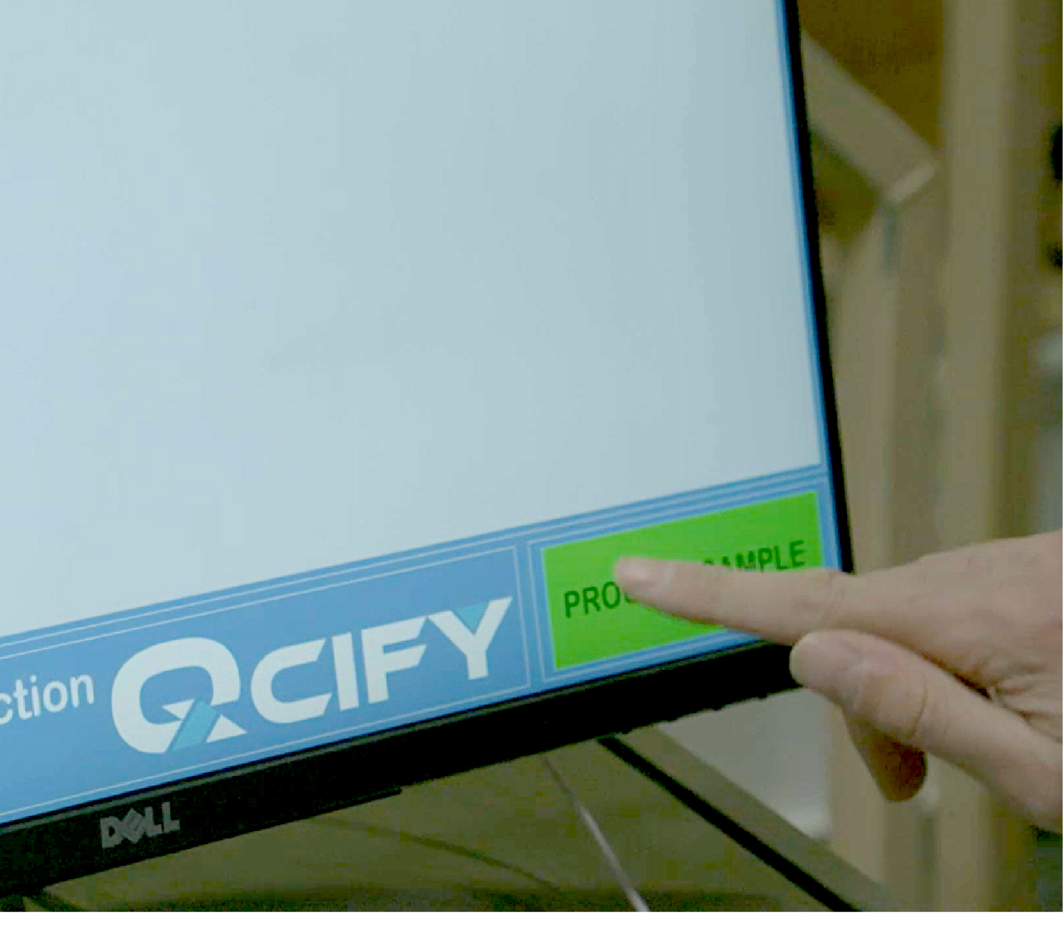 closeup of dell computer monitor with QCIFY logo and finger reaching out to tap green PRODUCT SAMPLE button