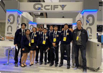 QCIFY team wearing dark navy and standing in front of a QCIFY booth at a convention centre