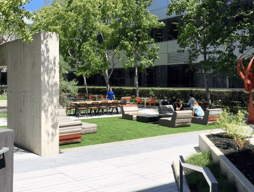 Courtyard outside of building with cement columns and relaxing sofa and table gathering areas and cement walkways